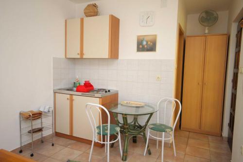 a kitchen with a table and chairs and a table and a counter at Studio Krk 3231a in Vrh