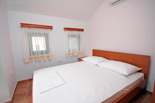 a bedroom with a bed with white sheets and windows at Double Room Rogoznica 3266a in Rogoznica