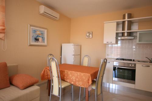 a kitchen with a table and chairs and a refrigerator at Apartments with a parking space Novalja, Pag - 3294 in Novalja