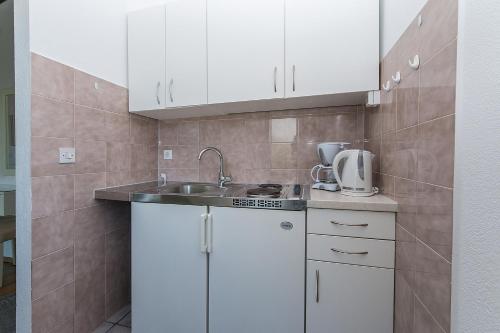 una cocina con armarios blancos y fregadero en Apartments and rooms with parking space Brela, Makarska - 2717 en Brela