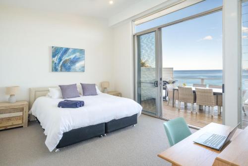 a bedroom with a bed and a desk with a laptop at The Sands Mollymook Luxury Beach House in Mollymook