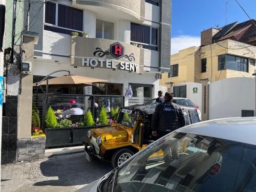 a man standing in front of a hotel sign with a truck at Hotel Seny in Ambato
