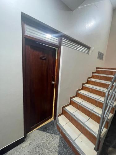 Un escalier mène à une porte en bois. dans l'établissement Alojamiento tahuari, à Iquitos