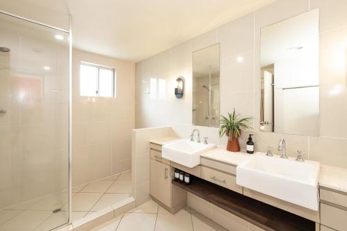 a bathroom with two sinks and a shower at Lantana Lakes - Resort Style Living in Cairns North