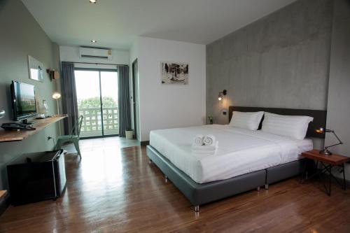 a bedroom with a large white bed and a television at Space59 Hotel in Ratchaburi