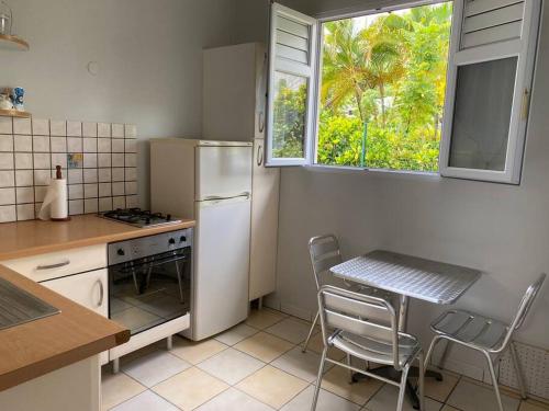 une cuisine avec un réfrigérateur, une table et une fenêtre dans l'établissement Maison du bonheur - 50 m de la plage Anse à l'Ane, à Les Trois-Îlets