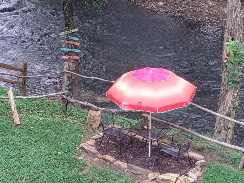 a table and chairs under an umbrella next to a river at Tranquil Creekside Mountain View Getaway in Clyde
