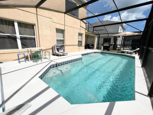 a swimming pool with a table and chairs next to a building at Fully Renovated, Quiet, Spacious Disney Themed Pool Home with Office in Kissimmee