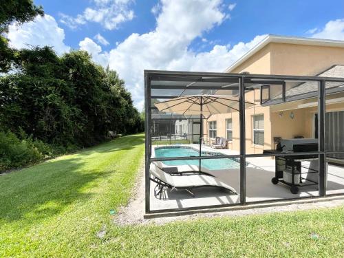 une terrasse avec une table, un parasol et une piscine dans l'établissement Fully Renovated, Quiet, Spacious Disney Themed Pool Home with Office, à Kissimmee