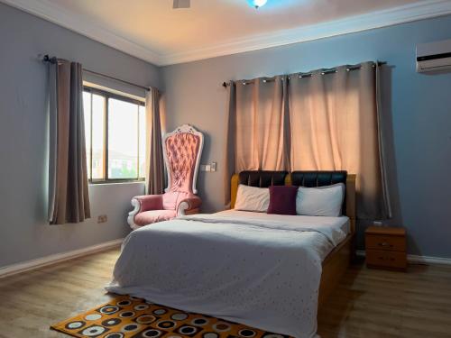 1 dormitorio con 1 cama y 1 silla rosa en T’s place, en Apenkwa