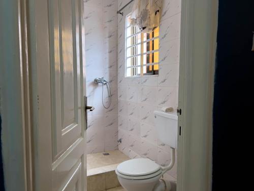 een witte badkamer met een toilet en een raam bij T’s place in Apenkwa