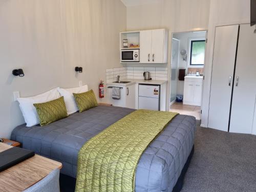 a bedroom with a large bed and a kitchen at Havelock Garden Motel in Havelock