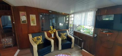 a living room with two chairs and a television at Pousada Cantuá in Ilha do Mel