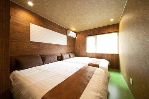 a bedroom with two beds and a window at The BEEHIVE OTARU in Otaru