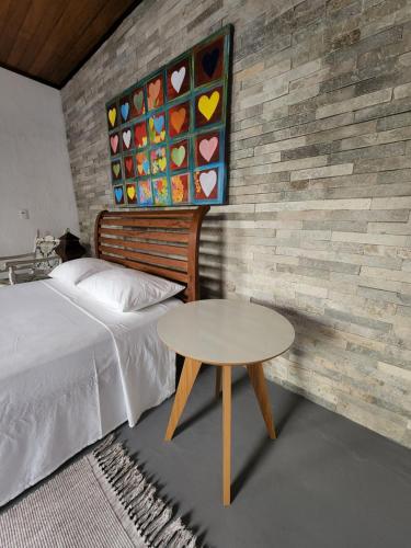 a bedroom with a bed and a table next to a wall at Buddha Suítes in Pipa