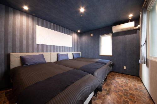 two beds in a bedroom with blue walls at The BEEHIVE OTARU in Otaru
