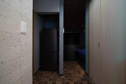 a hallway with a black refrigerator in a room at The BEEHIVE OTARU in Otaru