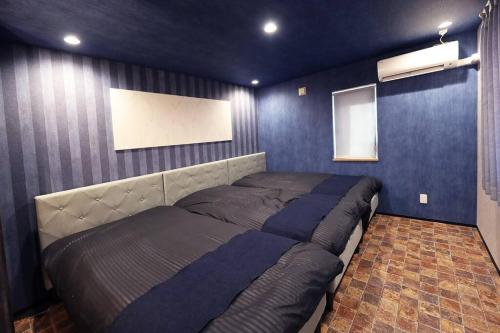 1 dormitorio con 1 cama grande y paredes azules en The BEEHIVE OTARU en Otaru