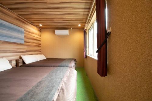 two beds in a small room with a window at The BEEHIVE OTARU in Otaru