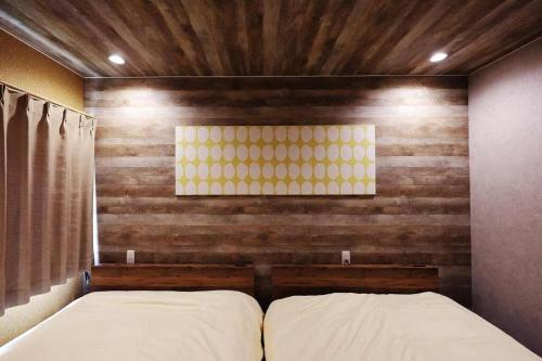a bed in a room with a wooden wall at The BEEHIVE OTARU in Otaru