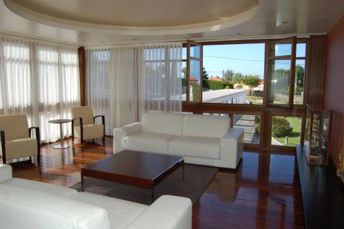 una sala de estar con sofás blancos y una mesa. en Hotel La Casona de Lupa, en El Peñedo