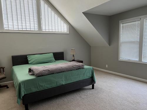 a bedroom with a bed with green sheets and two windows at Beautiful Private West Knoxville Home 2700sf, 4 Beds, 2 & half Baths in Knoxville