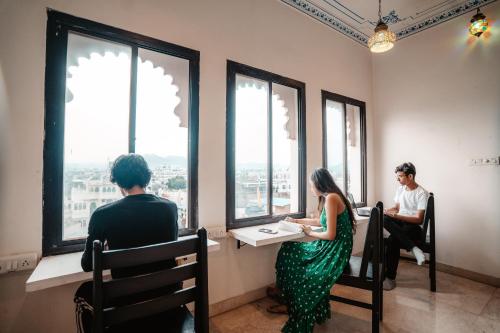 a couple of people sitting at a table looking out the window at Citylights By MUSAFIR in Udaipur