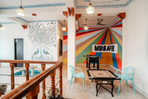a room with a mural and a table and chairs at Citylights By MUSAFIR in Udaipur