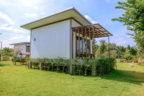 a small house with a large white wall at Baan Suan Thanwalai Khon Kaen in Khon Kaen