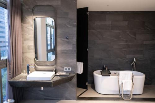 a bathroom with a sink and a tub and a mirror at M Hotel Saigon in Ho Chi Minh City