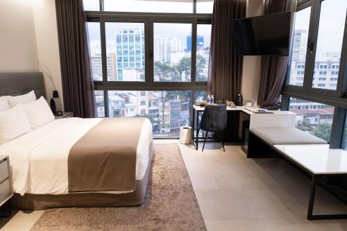 a hotel room with a bed and a desk and window at M Hotel Saigon in Ho Chi Minh City