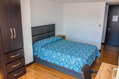 a bedroom with a bed with a blue comforter at Holly Hotel in Duitama