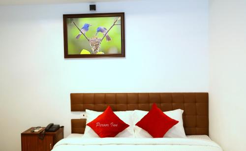 a bedroom with a bed with red and blue pillows at PEROOR INN in Trivandrum