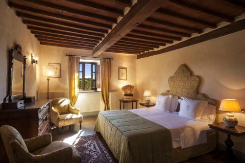 a bedroom with a bed and a chair and a window at Castello di Spaltenna Exclusive Resort & Spa in Gaiole in Chianti