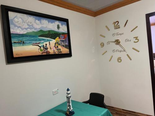 a clock on a wall with a picture of a beach at Posada Ashanty in Providencia