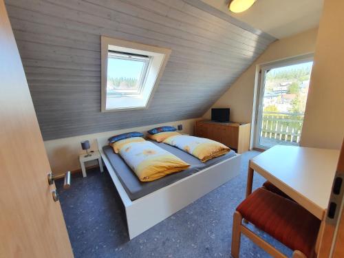 a bedroom with two beds and a table and a window at Ferienhaus Sonnengelb im Herzen des Schwarzwaldes in Schönwald