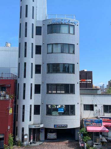 a tall white building with a sign on it at 4人で一緒に熊本の中心地の最も広く安価な部屋 KDY stay in Kumamoto