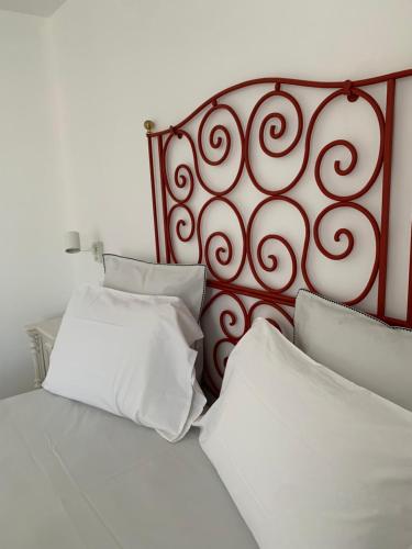 a bed with white pillows and a red head board at Le Case di Don Andrea in Minori