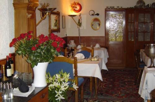 a dining room with a table and a vase of red flowers at Hotel & Restaurant Raisch in Steinwenden