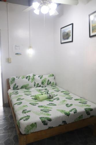 a bedroom with a bed with a green comforter at Ice Bear Bar & Tourist Inn in Dauis
