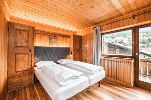 Habitación de madera con 2 camas y ventana en Chalet Scherlin en Ortisei