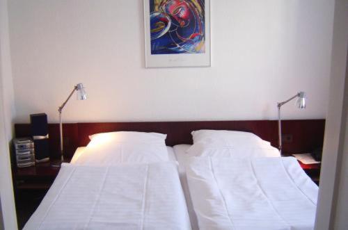 two beds in a bedroom with two lights on the wall at Hotel & Restaurant Raisch in Steinwenden