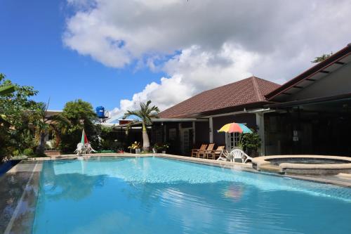 a swimming pool in front of a building with a house at Ice Bear Bar & Tourist Inn in Dauis