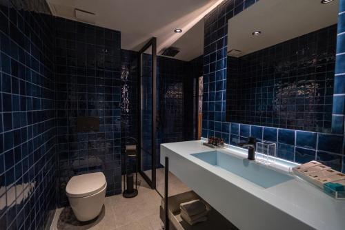 a blue tiled bathroom with a toilet and a sink at Zimmer Bosphorus Hotel in Istanbul