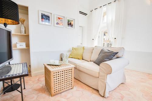 un salon avec un canapé blanc et une télévision dans l'établissement La Maison Mentone Lorgues, à Lorgues