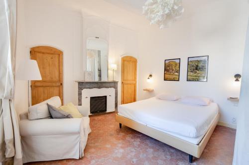 une chambre avec un lit, un canapé et une cheminée dans l'établissement La Maison Mentone Lorgues, à Lorgues