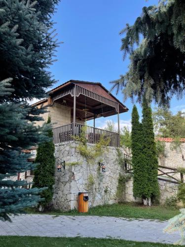 a building with a porch on top of a stone wall at Kirovi Tun in Dilijan