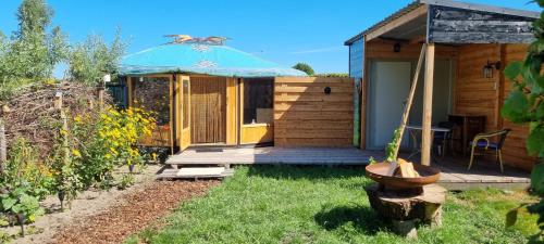 a small wooden cabin with a deck and an umbrella at Yurt in Liempde