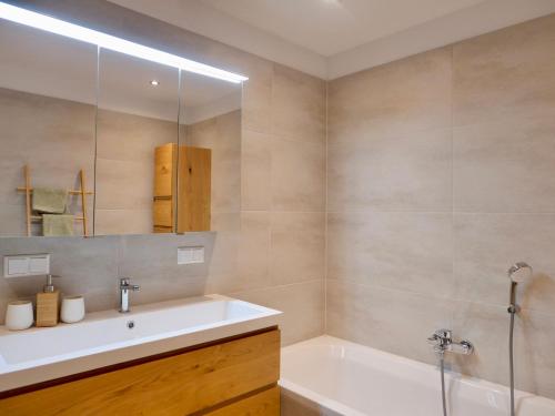 ein Badezimmer mit einem Waschbecken, einer Badewanne und einem Spiegel in der Unterkunft Apartment Auszeit in Gröbming