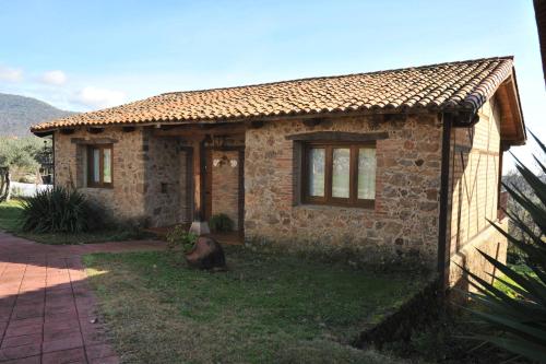 a small brick house with a cow sitting in the yard at Hotel Rural Hosteria Fontivieja TR-CC-195 in Losar de la Vera